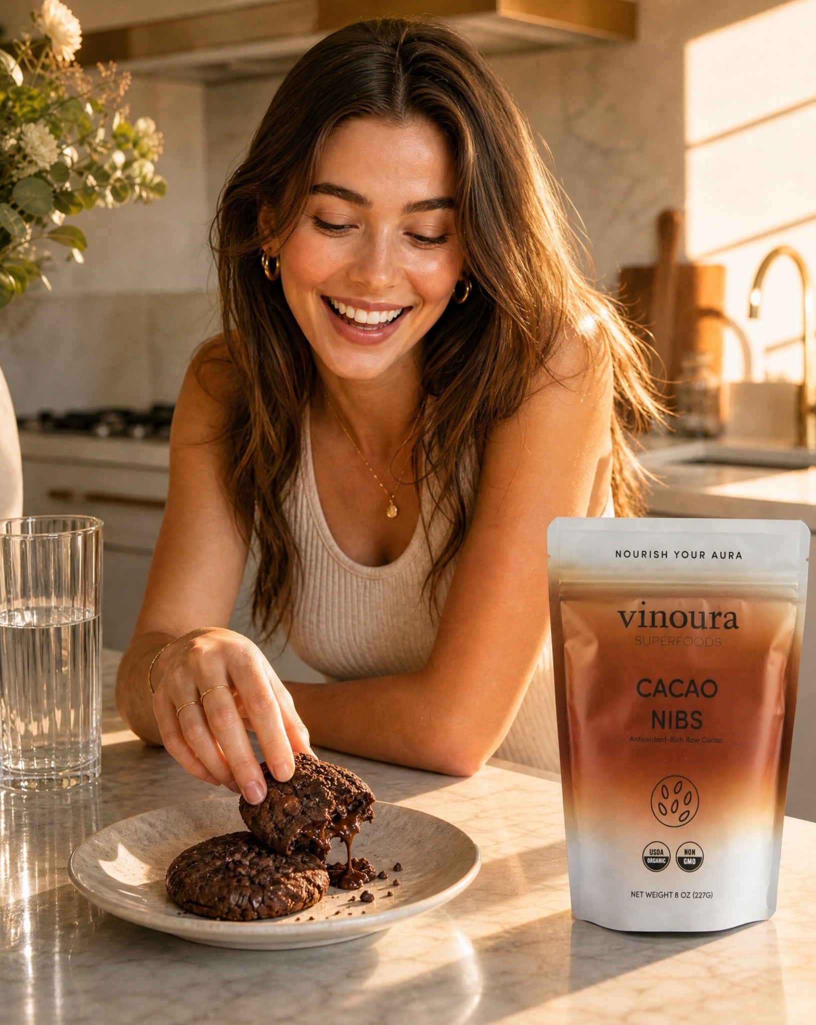 Woman enjoying a cookie with a package of vinoura cacao nibs in a kitchen.
